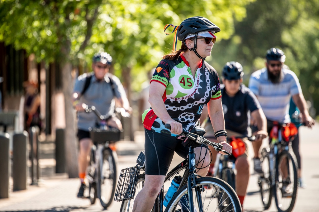 Becca Freed on a bicycle, starting a group ride, with three other riders in the background. 